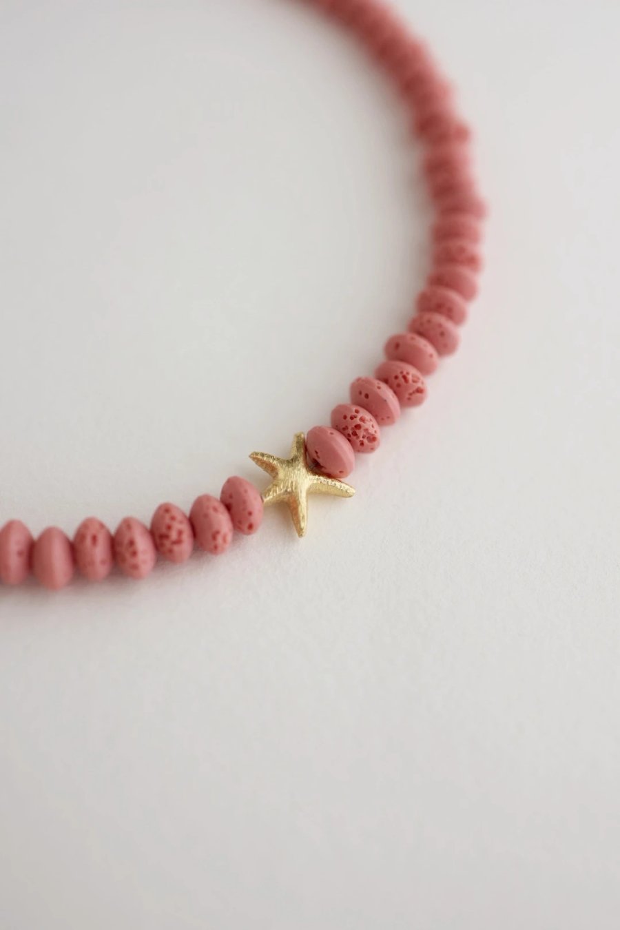 Adjustable pink volcanic lava necklace with a starfish pendant and gold-plated silver elements, handmade