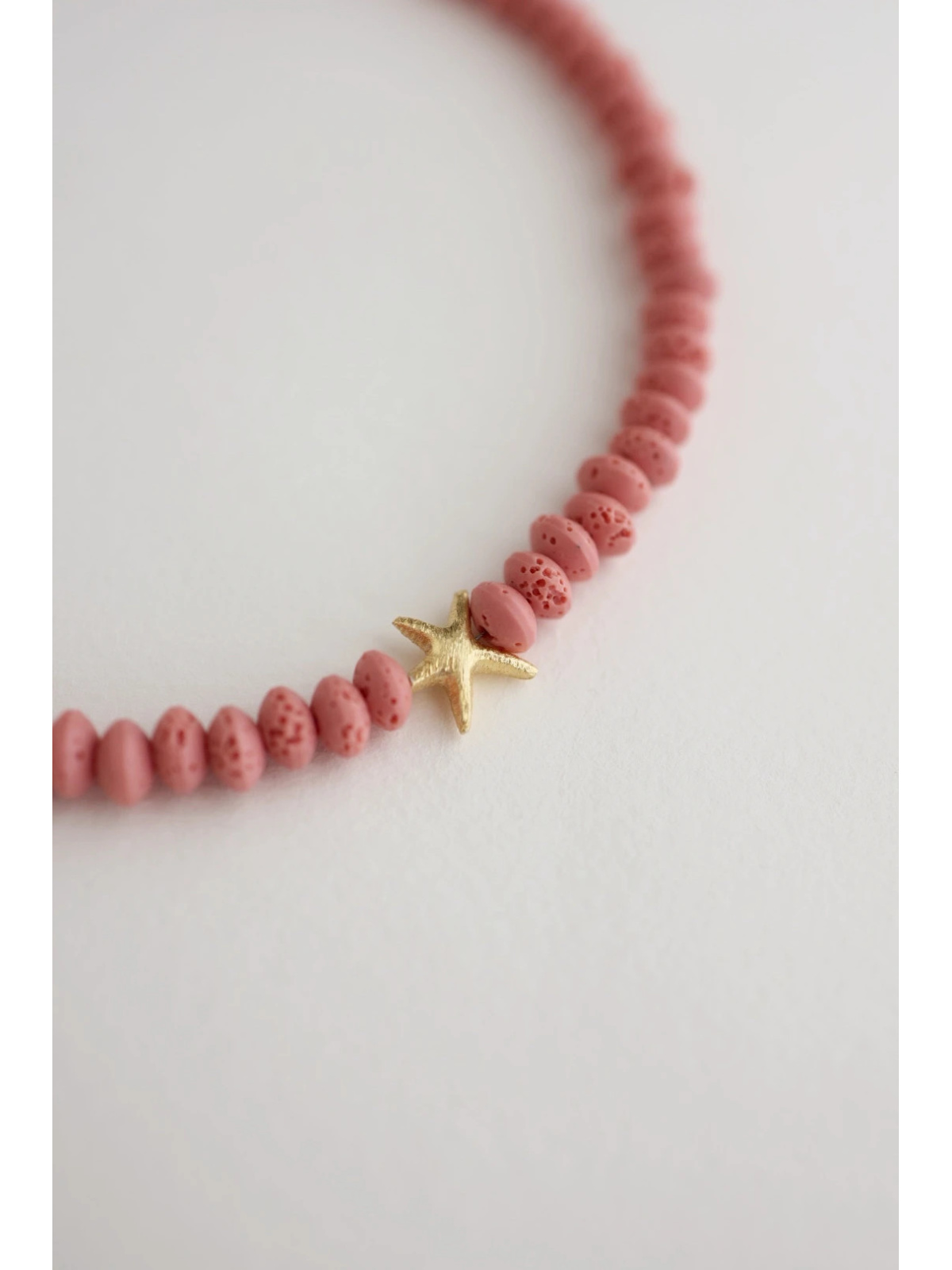 Adjustable pink volcanic lava necklace with a starfish pendant and gold-plated silver elements, handmade