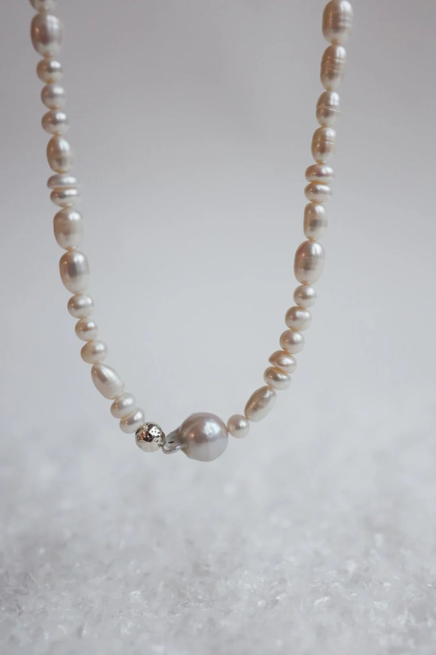 Necklace of cultured freshwater pearls, including baroque pearls, with a hammered bead of silver and, handmade